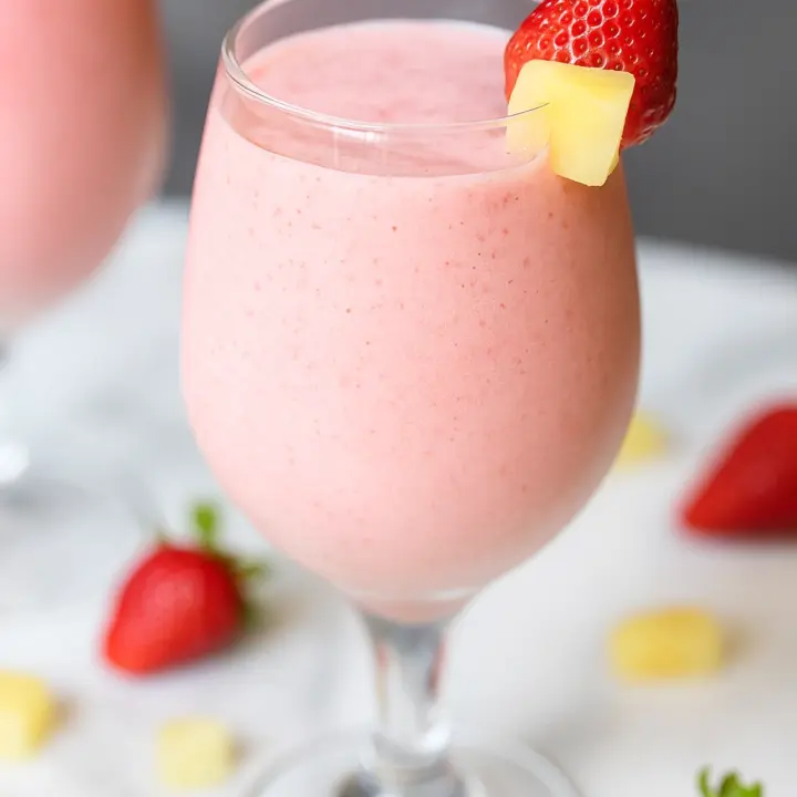 Strawberry colada drink with strawberries and pineapple in a fluted glass